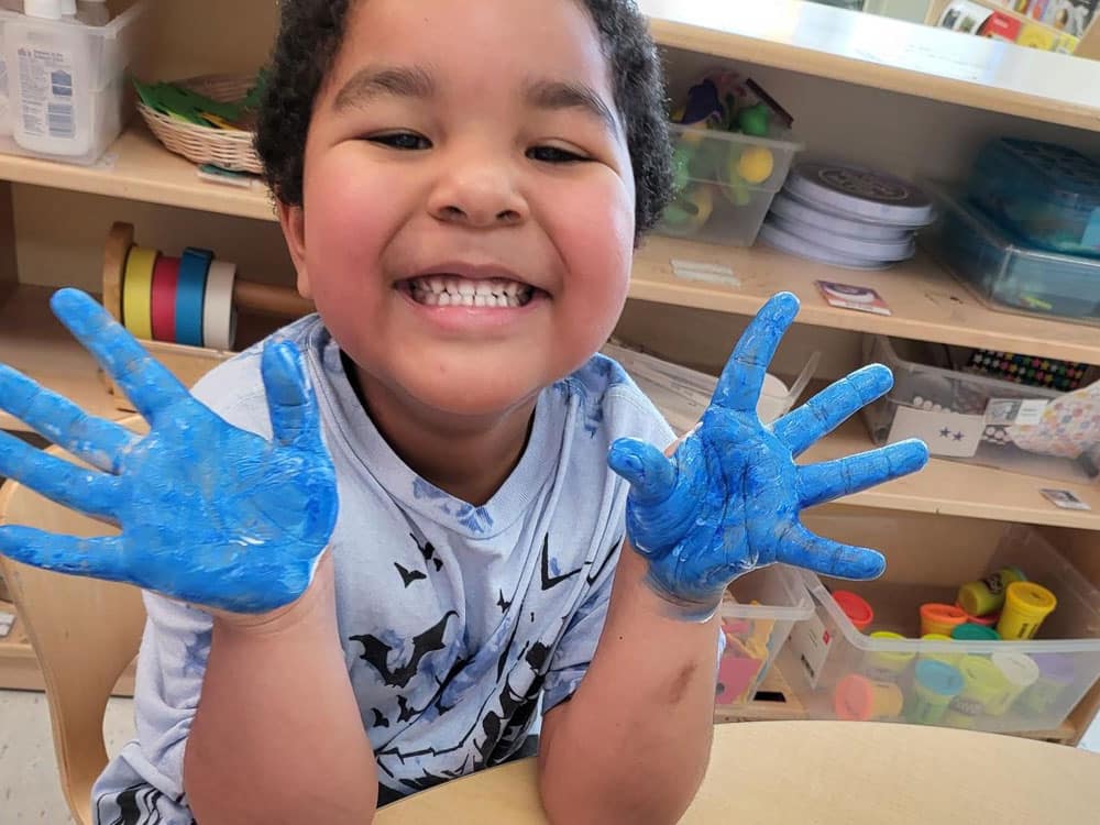 Boy smiling with blue paint covered hands